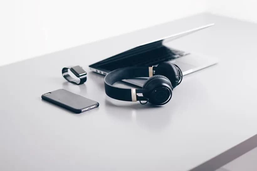 Headphones, smart watch and a phone on a light desk