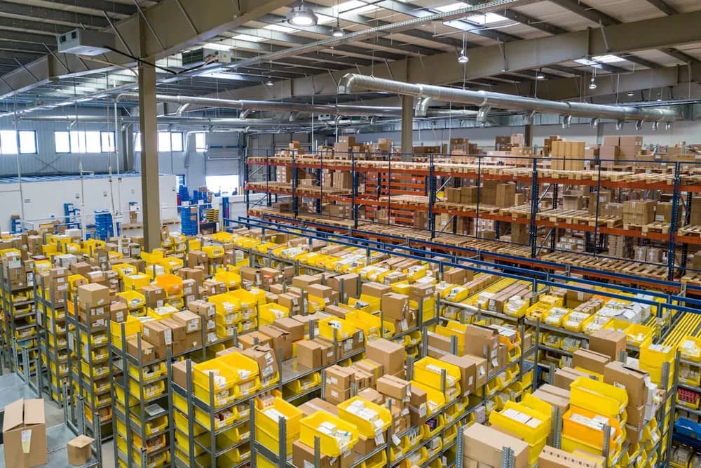 Warehouse aisles stacked with yellow bins and boxes of surplus goods