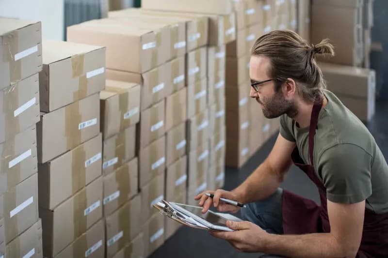 Warehouse worker checking stock against a tablet between storage racks
