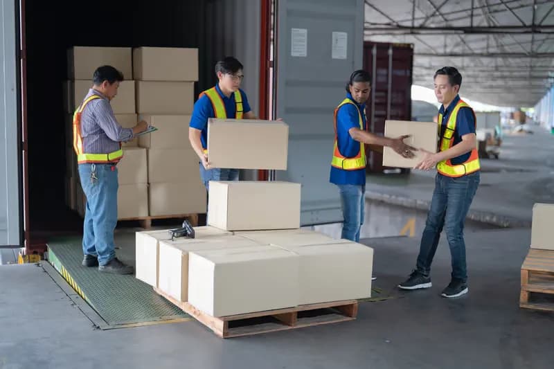 Warehouse workers in high-visibility vests handing over cardboard boxes