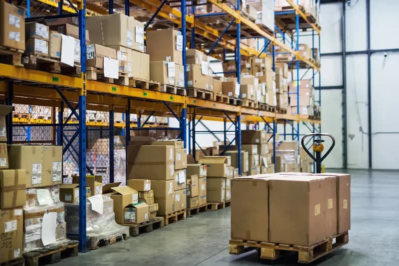 Warehouse racking stacked with cardboard boxes beside a loaded pallet