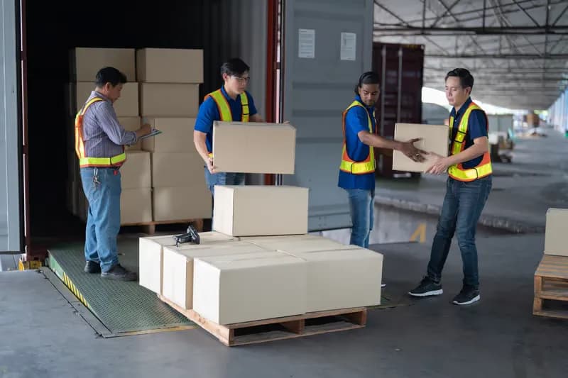 Warehouse workers in high-visibility vests handing over cardboard boxes