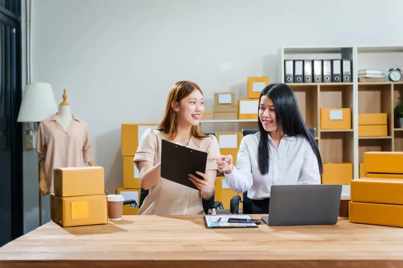 Two sellers reviewing orders in a small stockroom